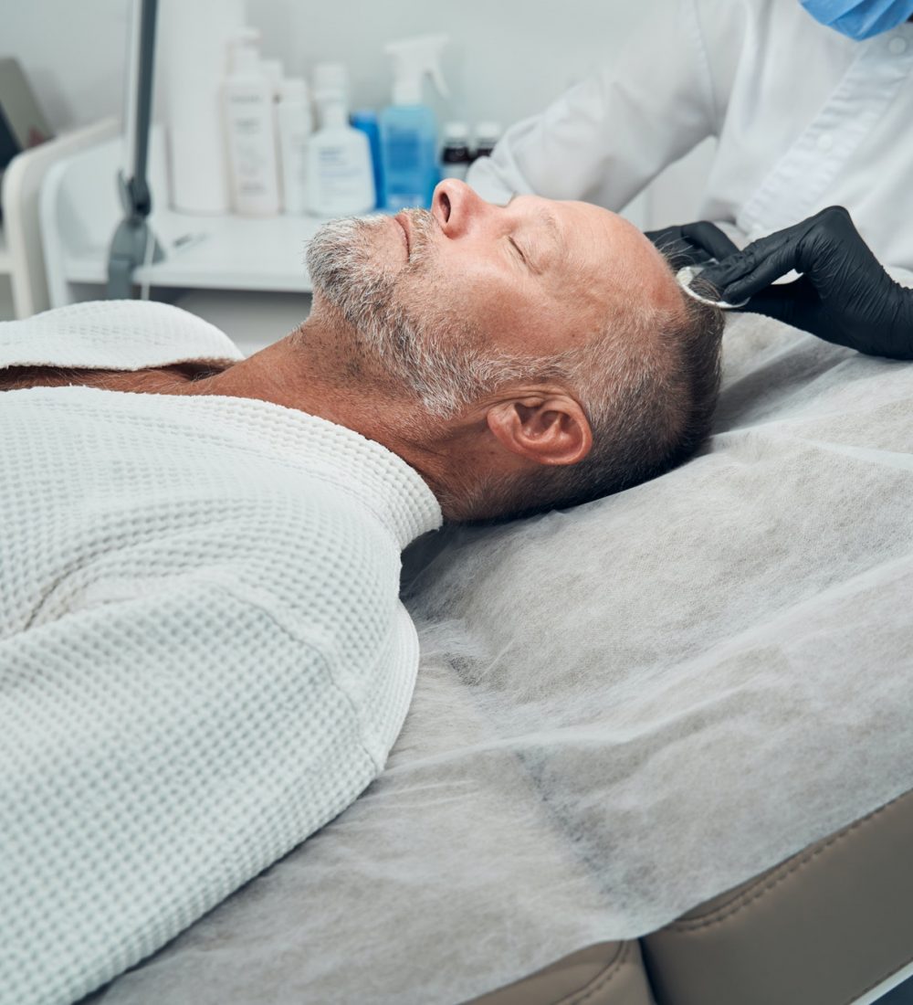 Man receiving hair loss treatment in cosmetology clinic